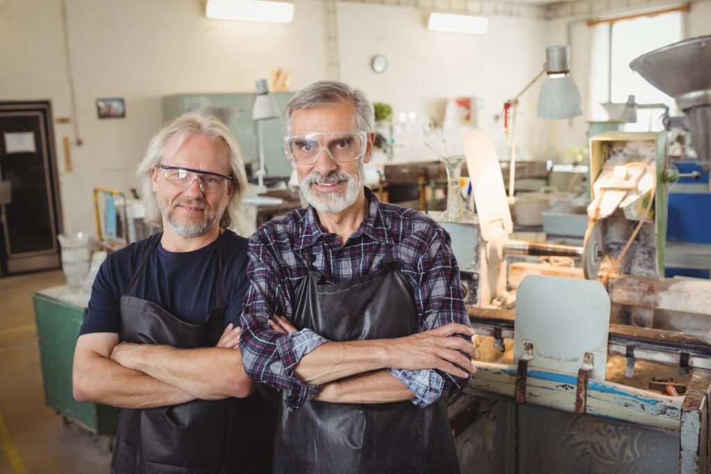 portrait of team of glassblowers with arms crossed at glassblowing factory